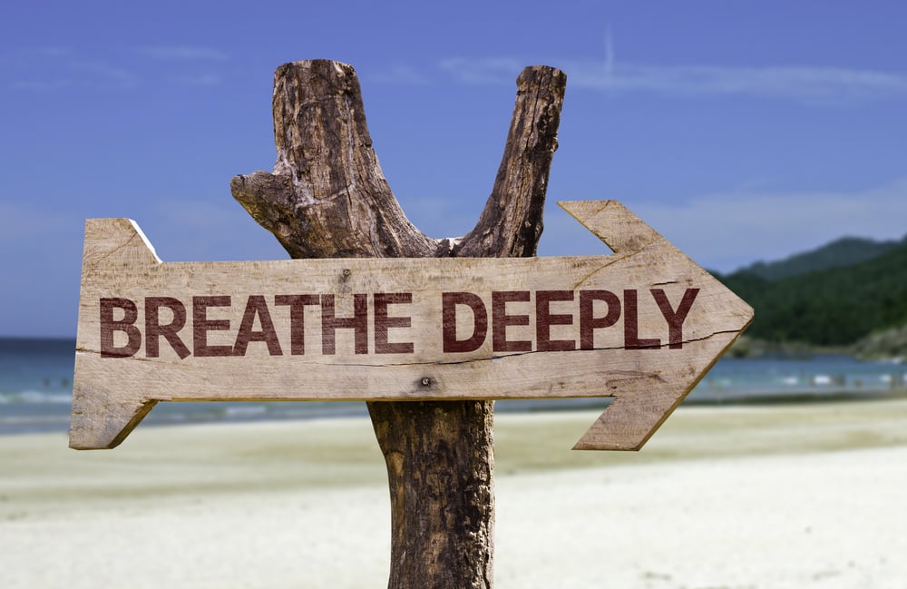 Breathe Deeply wooden sign with a beach on background