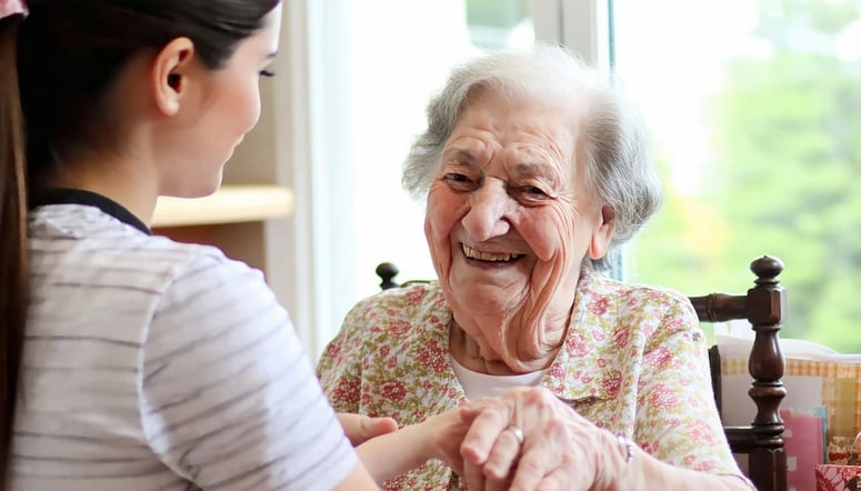 An elderly woman smiling at home while a caregiver