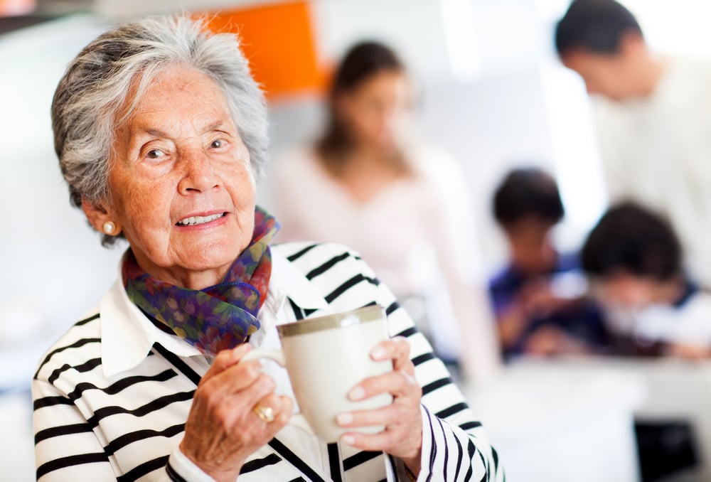 Old woman holding a cup of tea and smiling