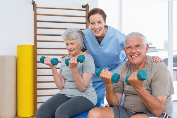 Female therapist assisting senior couple with dumbbells in the medical office