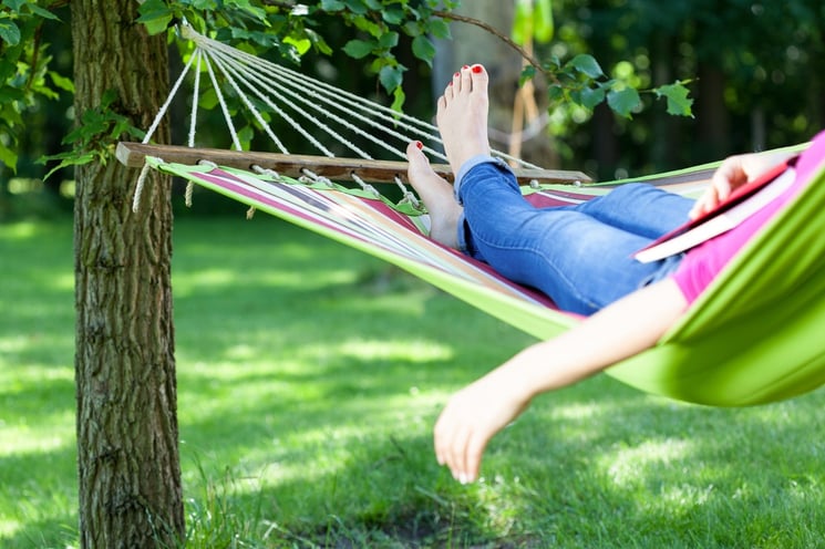 Young lady resting on hammock with book summer