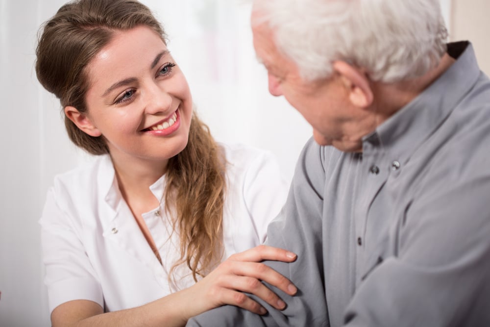 Picture of smiling nurse assisting senior man with Alzheimers