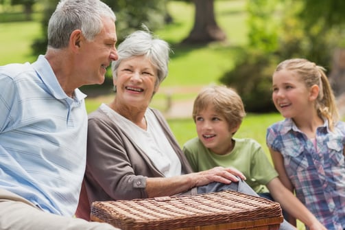 Portrait of a smiling senior couple and grandchildren at the park