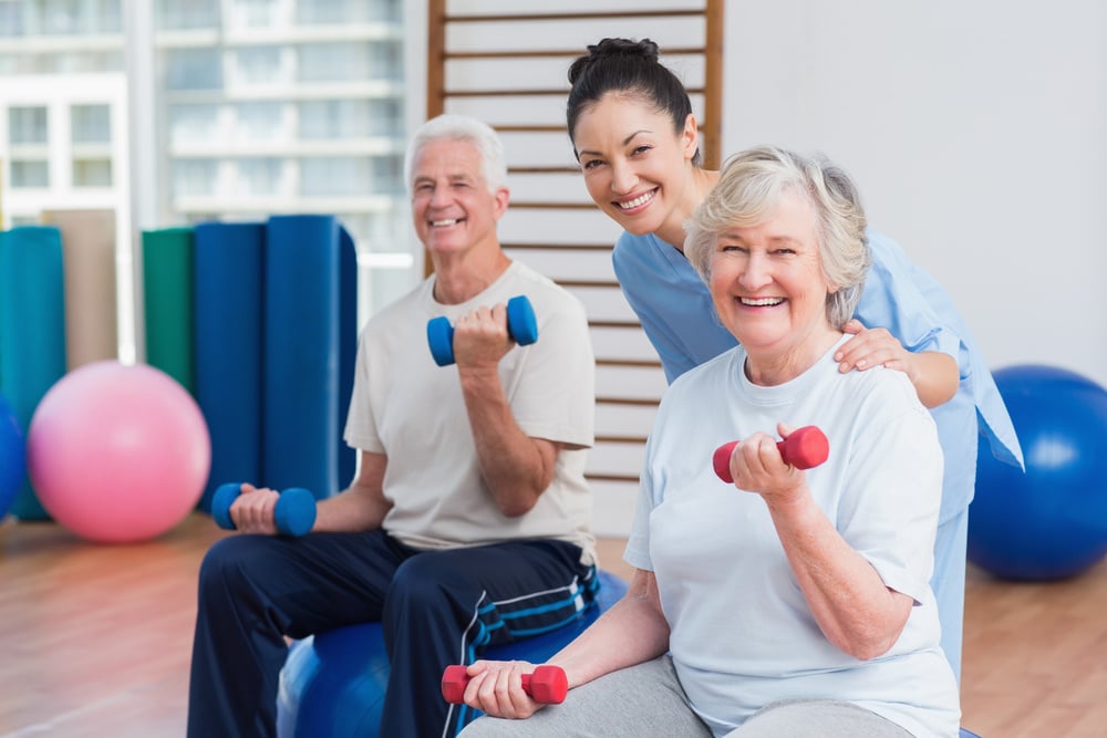 Caregiver with senior couple in gym