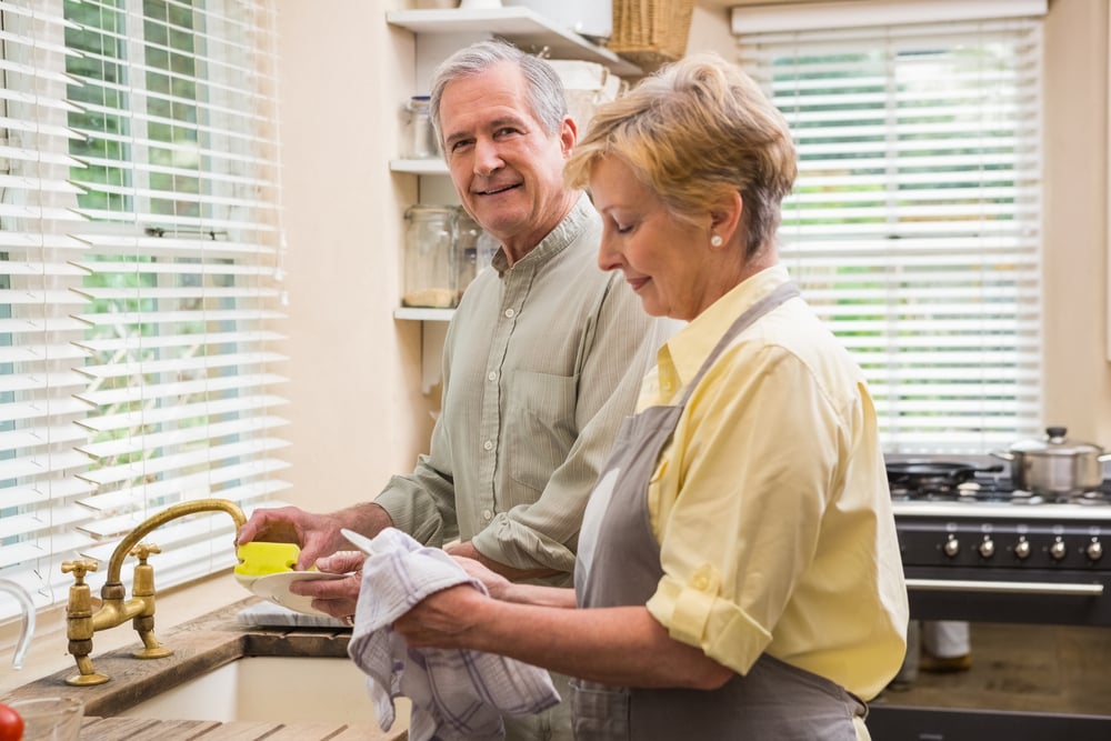 Senior couple washing the dishes at home in the kitchen