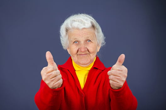 Closeup portrait senior, mature, happy, smiling excited natural woman giving thumbs up sign with fingers, isolated blue background. Positive emotions, facial expressions, symbols, feelings, attitude